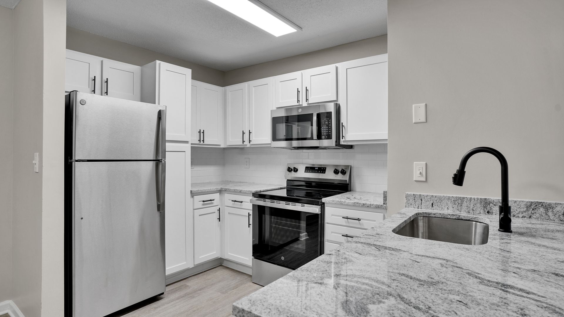 Apartment building with brick and beige siding, a walkway, and a blue sky.