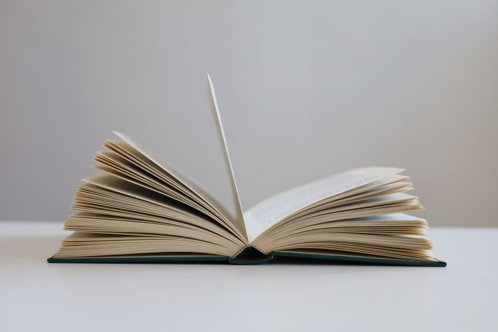 An open book is sitting on a white table.