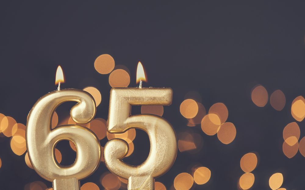 A gold birthday candle in the shape of the number 65.