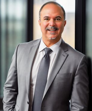 Kyle Kay is smiling in a gray suit and tie 