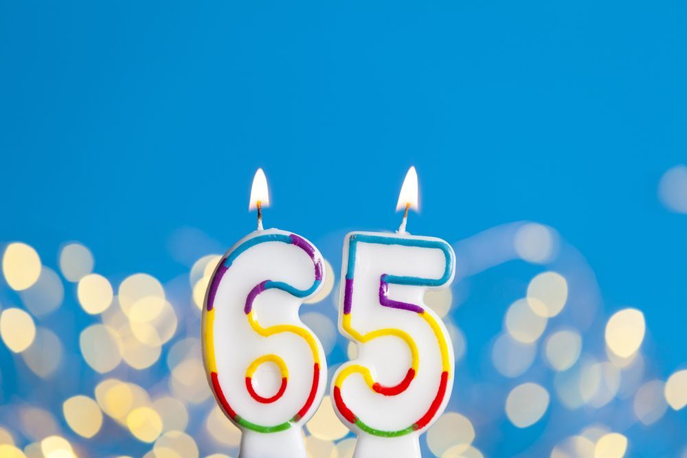 Two birthday candles in the shape of the number 65 on a blue background.