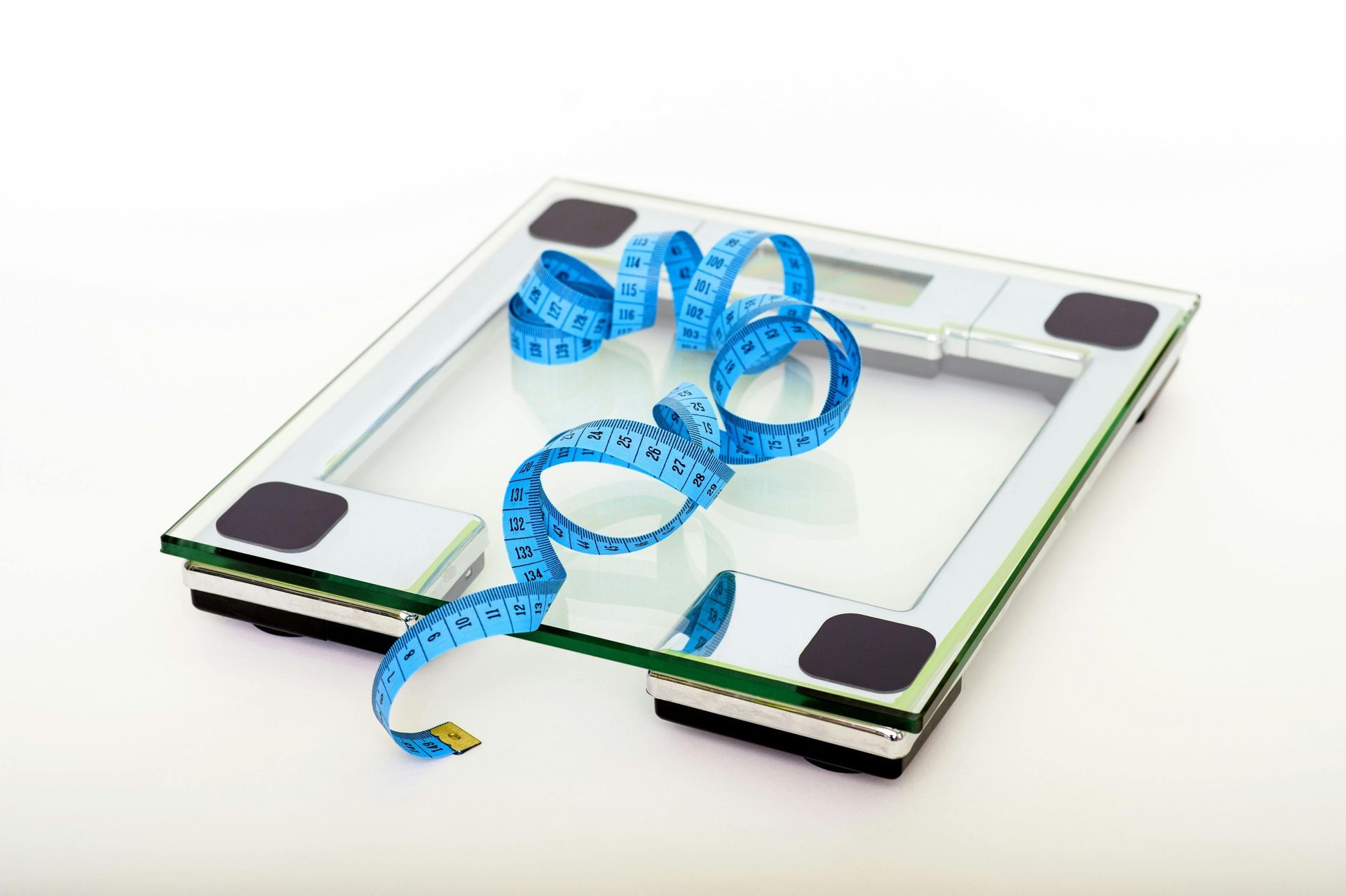 A bathroom scale with a blue measuring tape on top, white background.