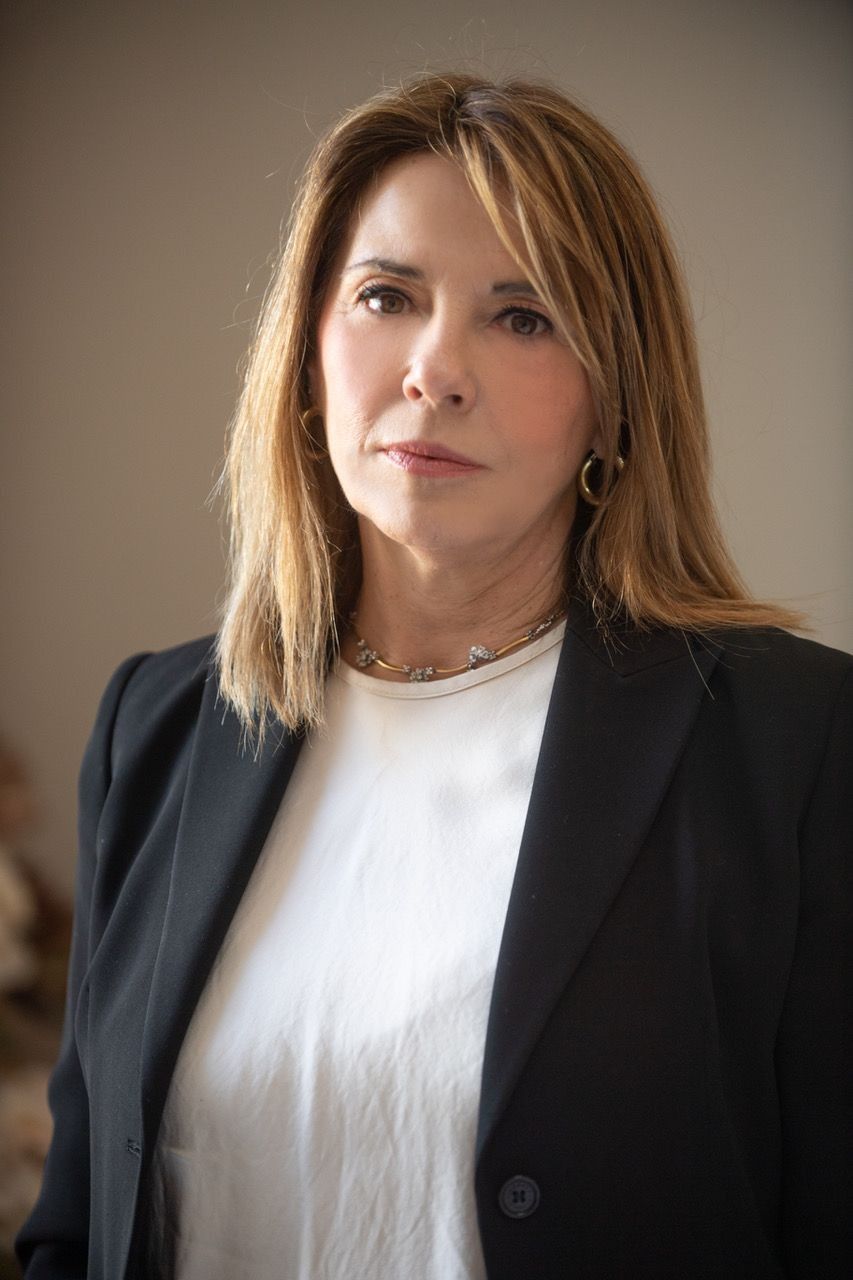 Donna con blazer nero e camicia bianca, dall'aria seria.