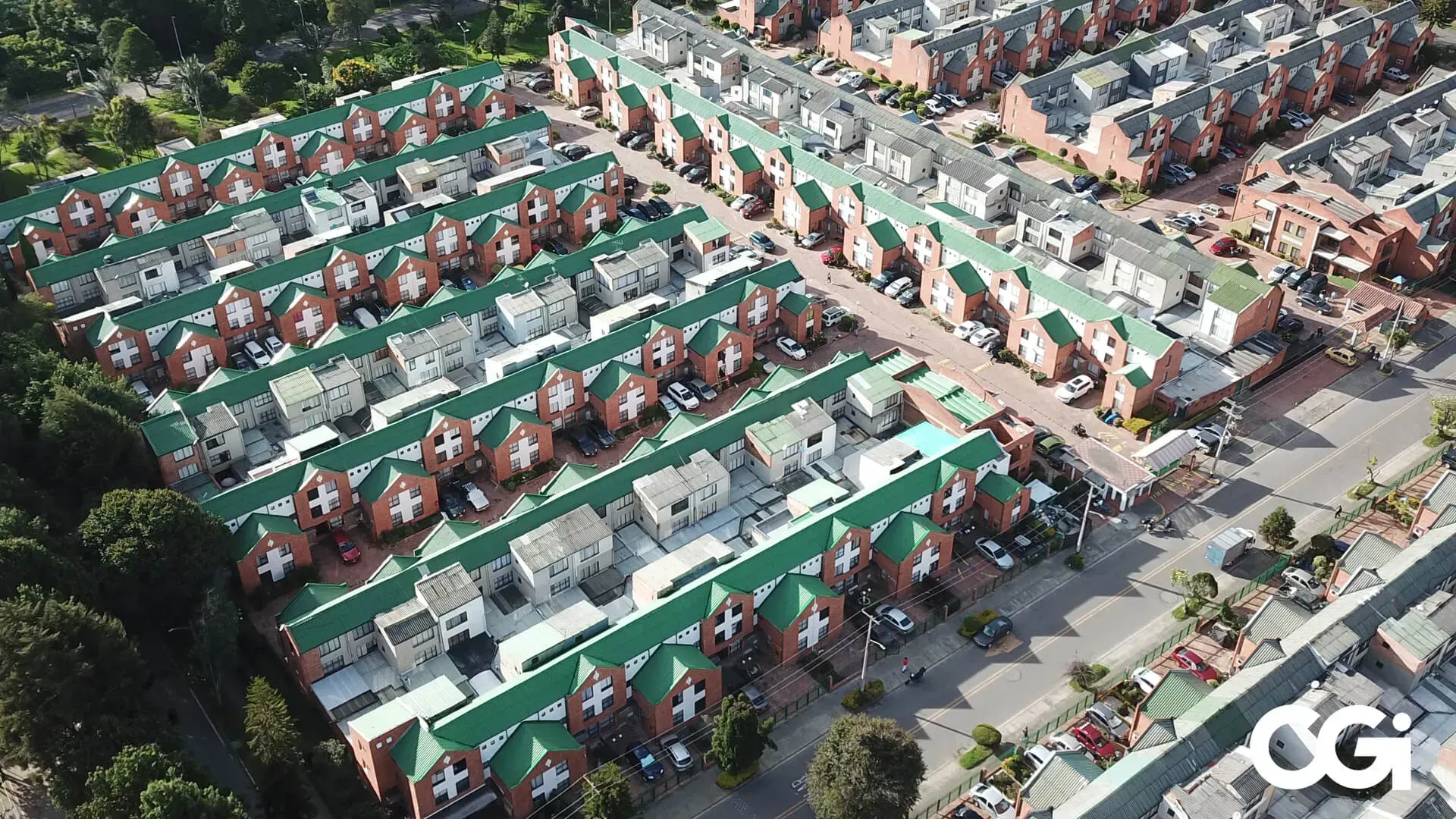 Vista aérea de un gran vecindario suburbano con casas de ladrillo, techos verdes y acceso a la calle.