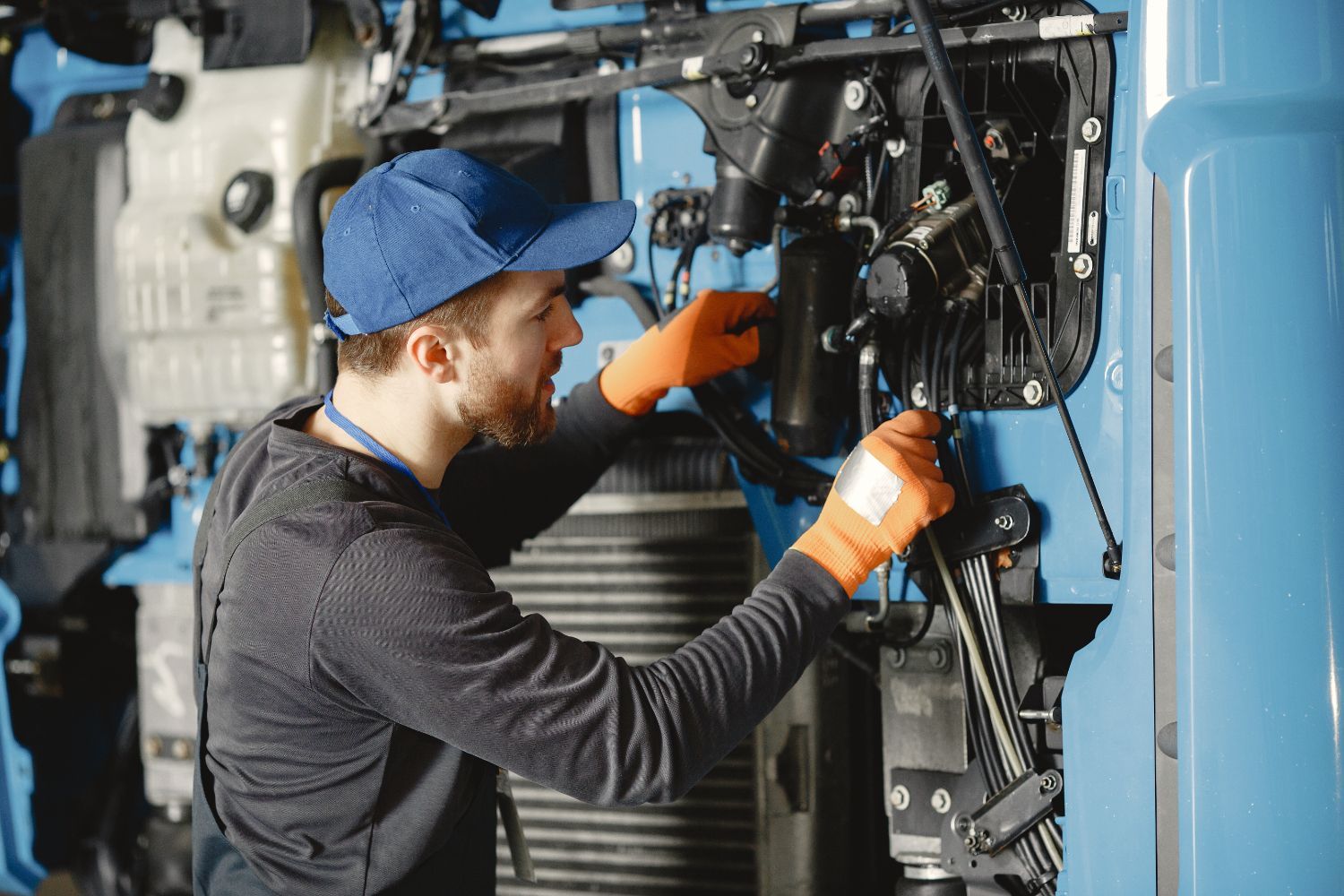 Un hombre está trabajando en el motor de un camión azul.