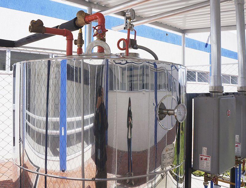 Un hombre está parado frente a un gran tanque de acero inoxidable.
