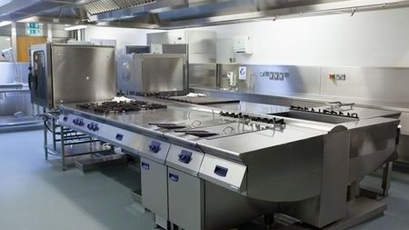 Cocina comercial con equipo de cocción de acero inoxidable y espacio de trabajo.