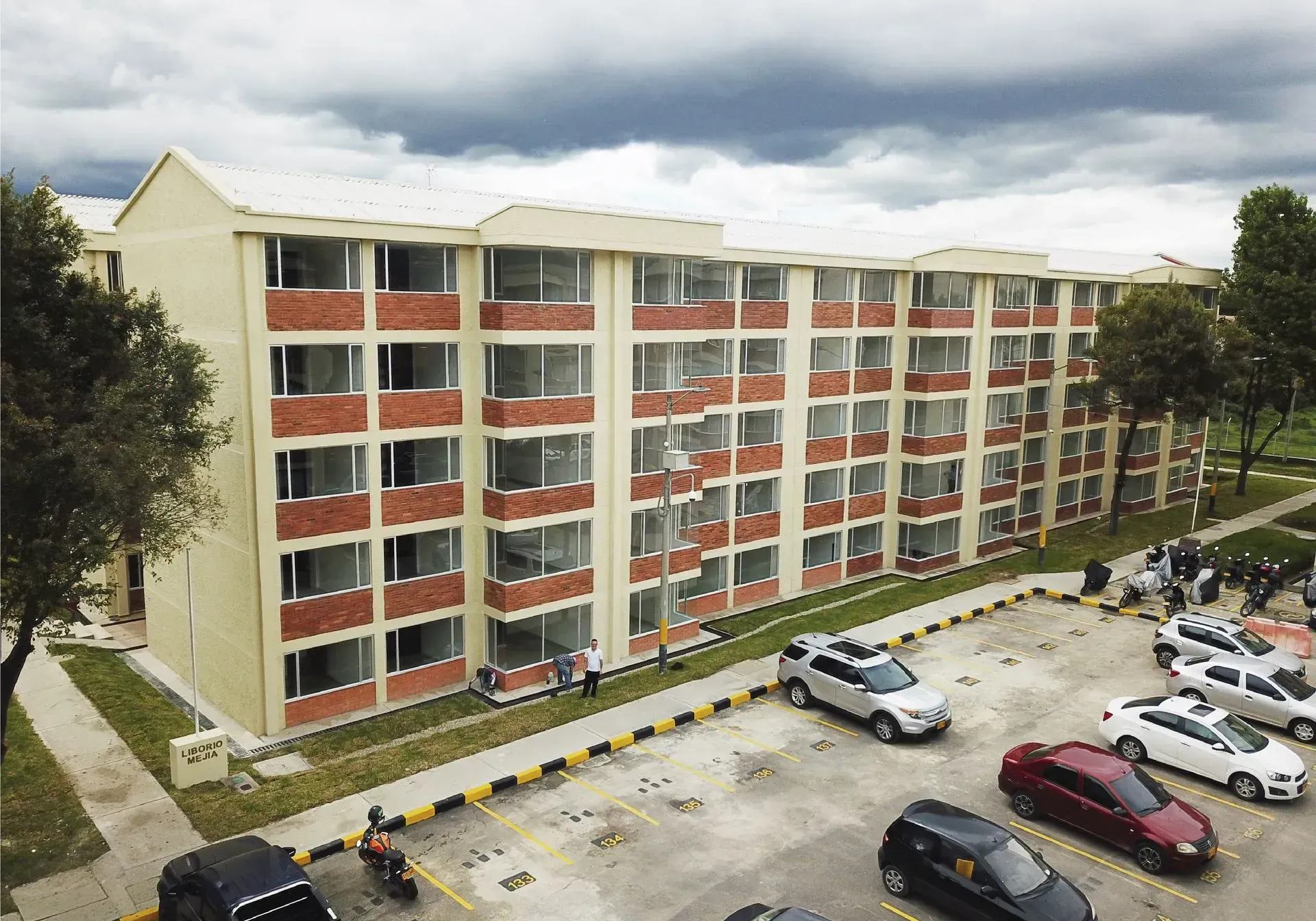 Edificio de apartamentos de varios pisos con coches estacionados en el frente.