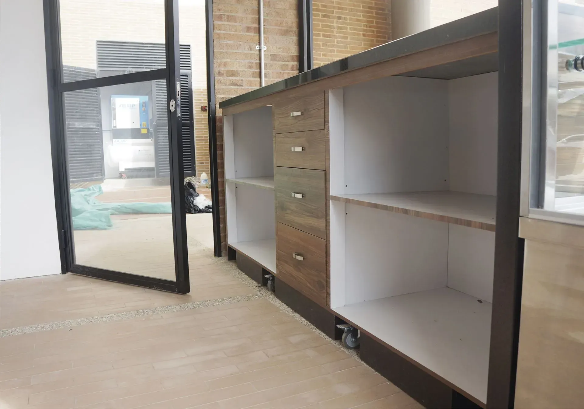Armario empotrado con puertas abiertas, estantes y cajones. Interior con estantes blancos y cajones en tonos madera. Marco de puerta negro al fondo.