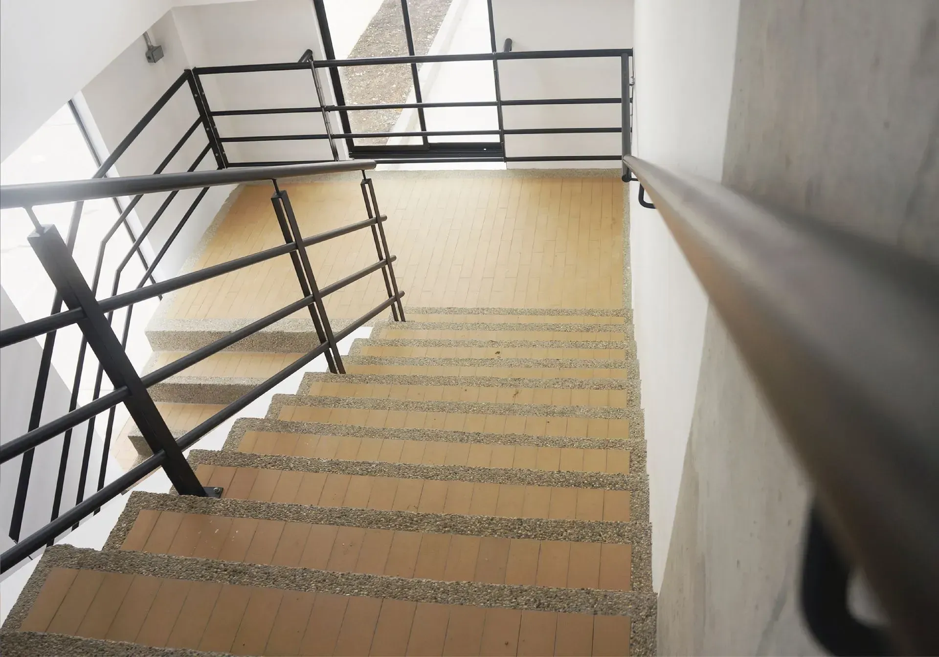 Escalera con barandilla metálica. La escalera es beige y baja.