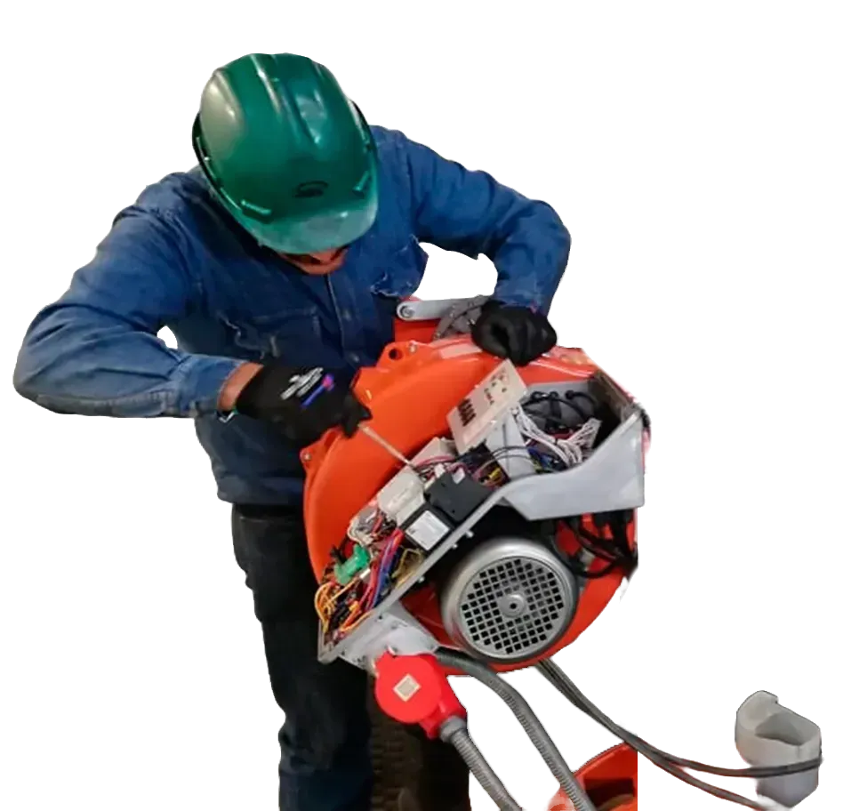 Persona con equipo de seguridad reparando máquina naranja, utilizando un destornillador.