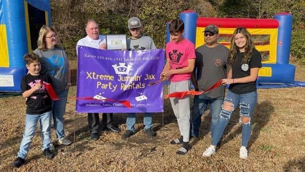 Group holding a purple banner at an outdoor inflatable event under sunny skies