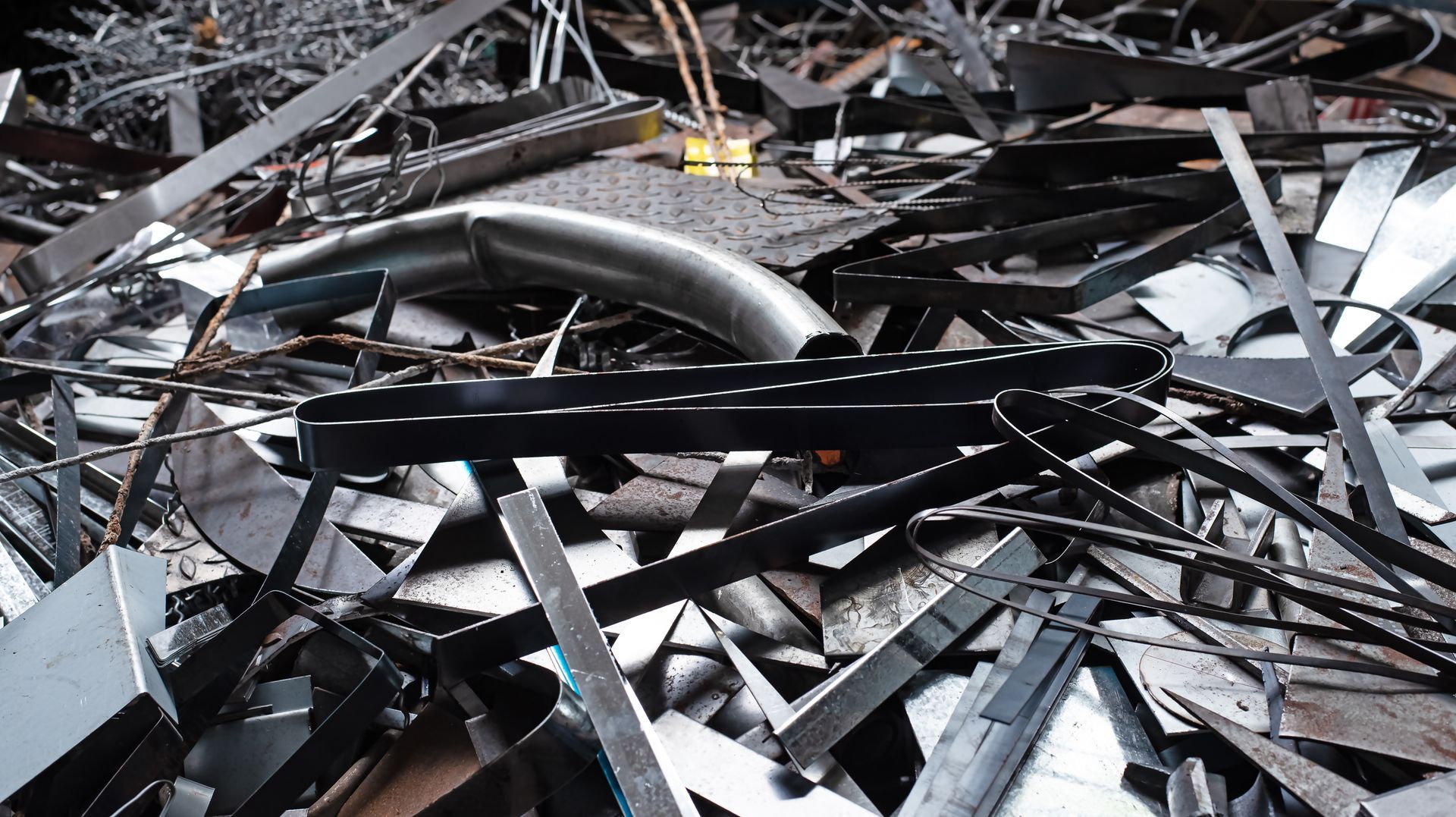 Piles of twisted black and gray metal scrap scattered across the ground in an industrial wreckage scene