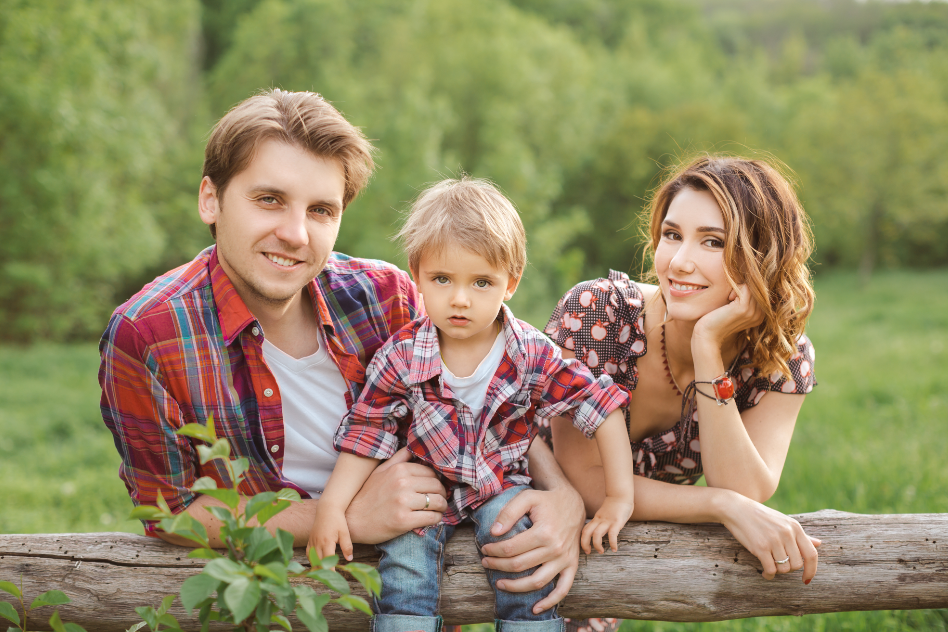 Man in plaid shirt smiles at child from car window.