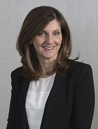A woman in a black jacket and white shirt is smiling for the camera.