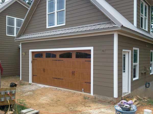 A brown house with a wooden garage door and windows