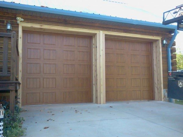 A garage with two wooden garage doors and a concrete driveway