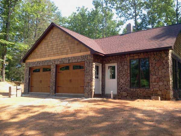 A house with a garage and a driveway is surrounded by trees.