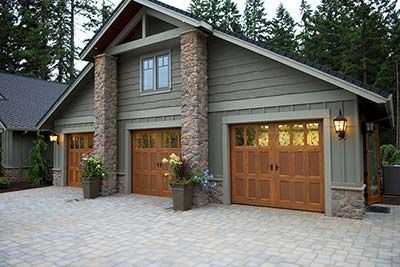 A house with three garage doors and a brick driveway