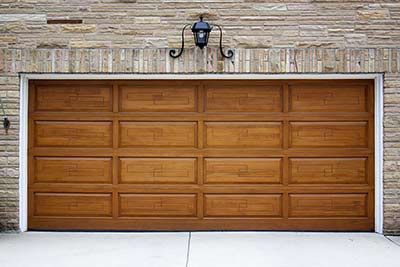 A wooden garage door is sitting in front of a brick wall.