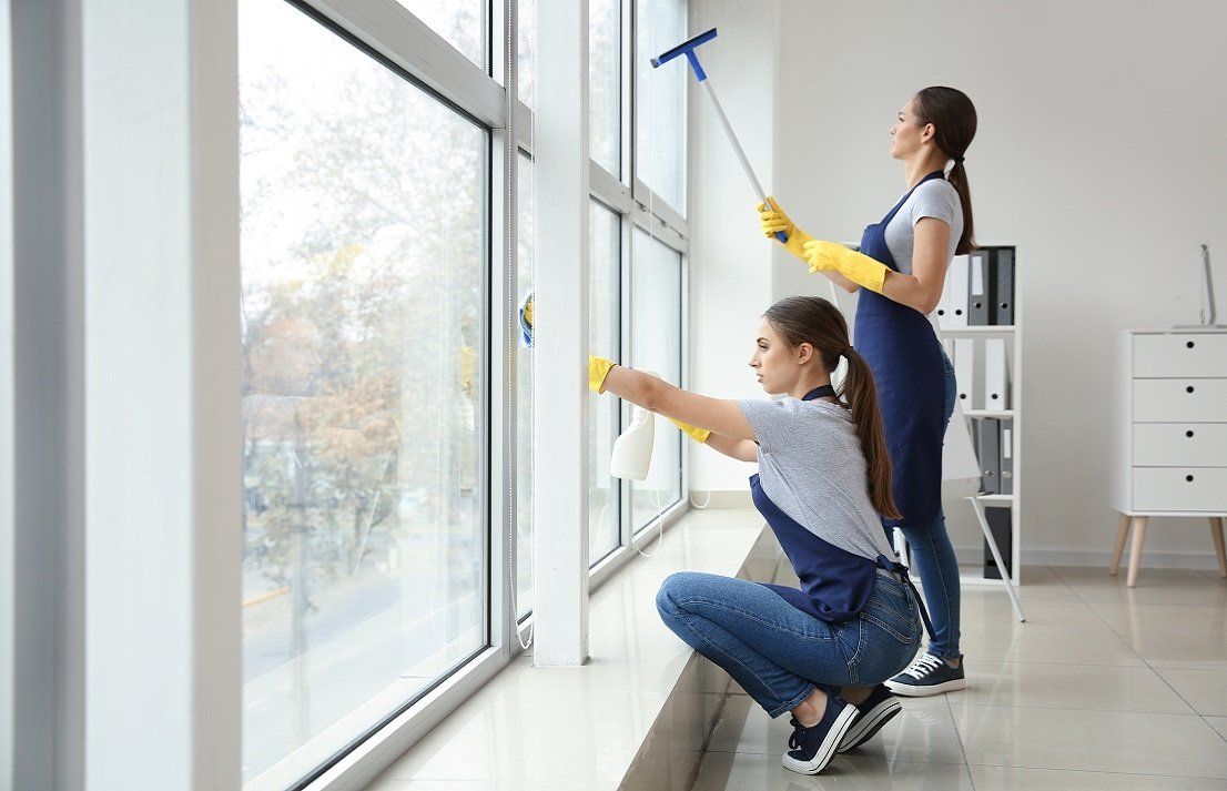 Two professional cleaners are cleaning the windows of an office space in Bunbury, WA.