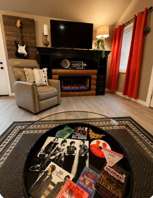 Cozy living room with fireplace, TV, armchair, and a patterned rug featuring memorabilia cover art.
