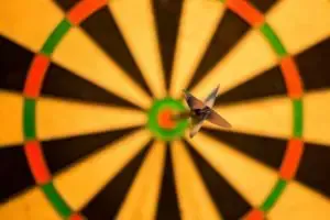A dart hitting the bullseye on a colorful, radiating dartboard.