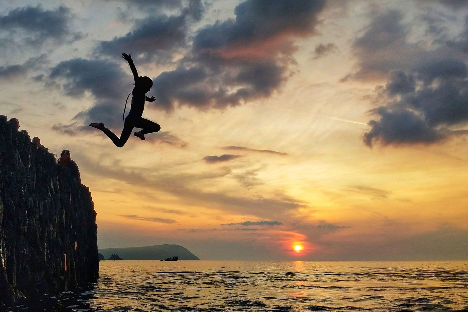 Girl jumping off a cliff into the water