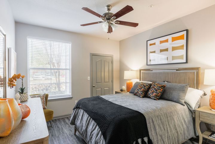 Bedroom with bed, art, and orange accents; neutral walls, wood trim.