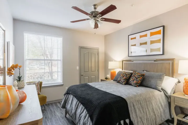 Bedroom with bed, art, and orange accents; neutral walls, wood trim.