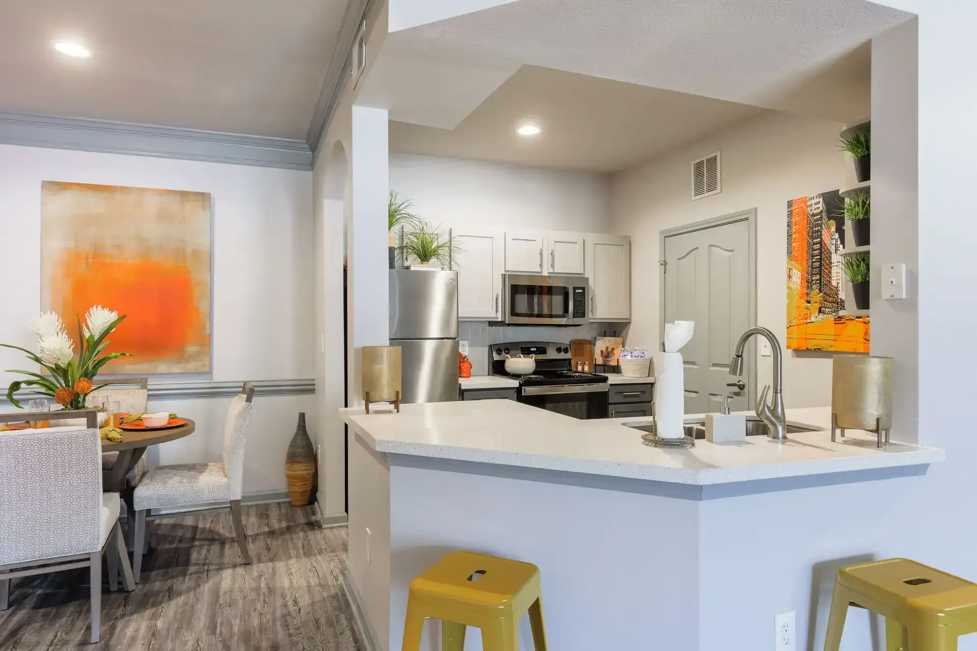 Kitchen with white countertops, stainless steel appliances, and yellow bar stools.