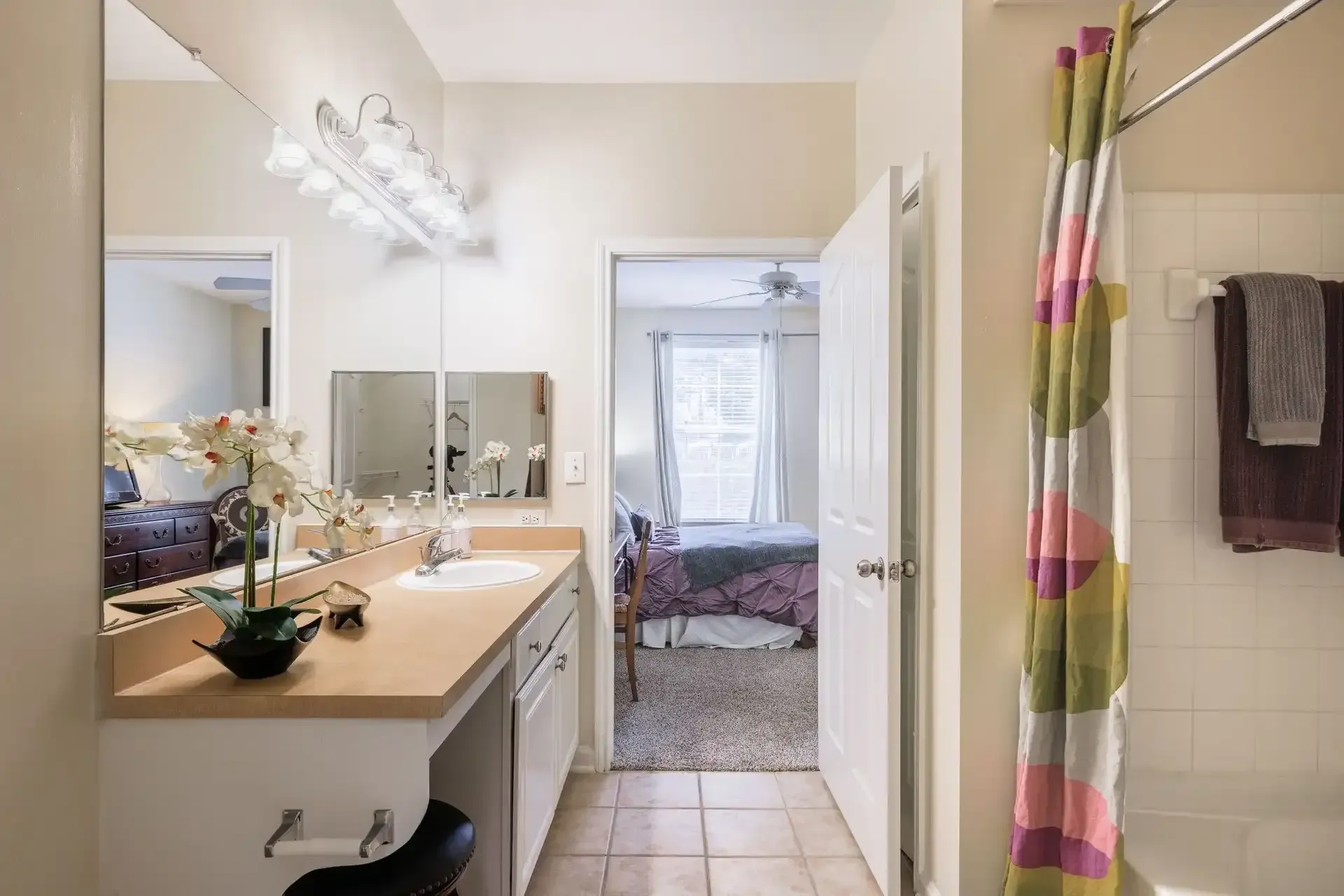 Bathroom with vanity, open door to bedroom, shower curtain.