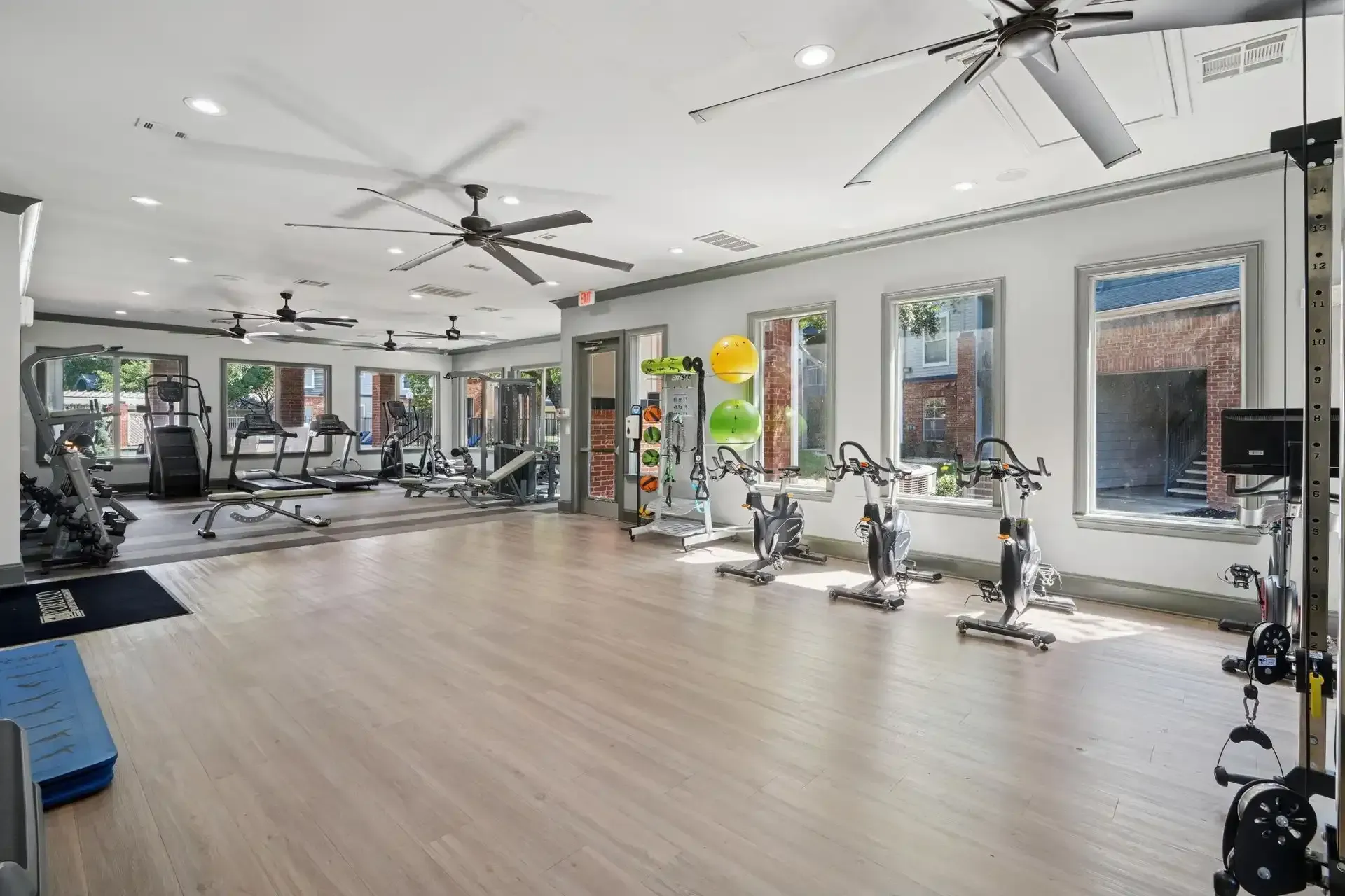 Gym interior with treadmills, weights, exercise bikes, and ceiling fans.