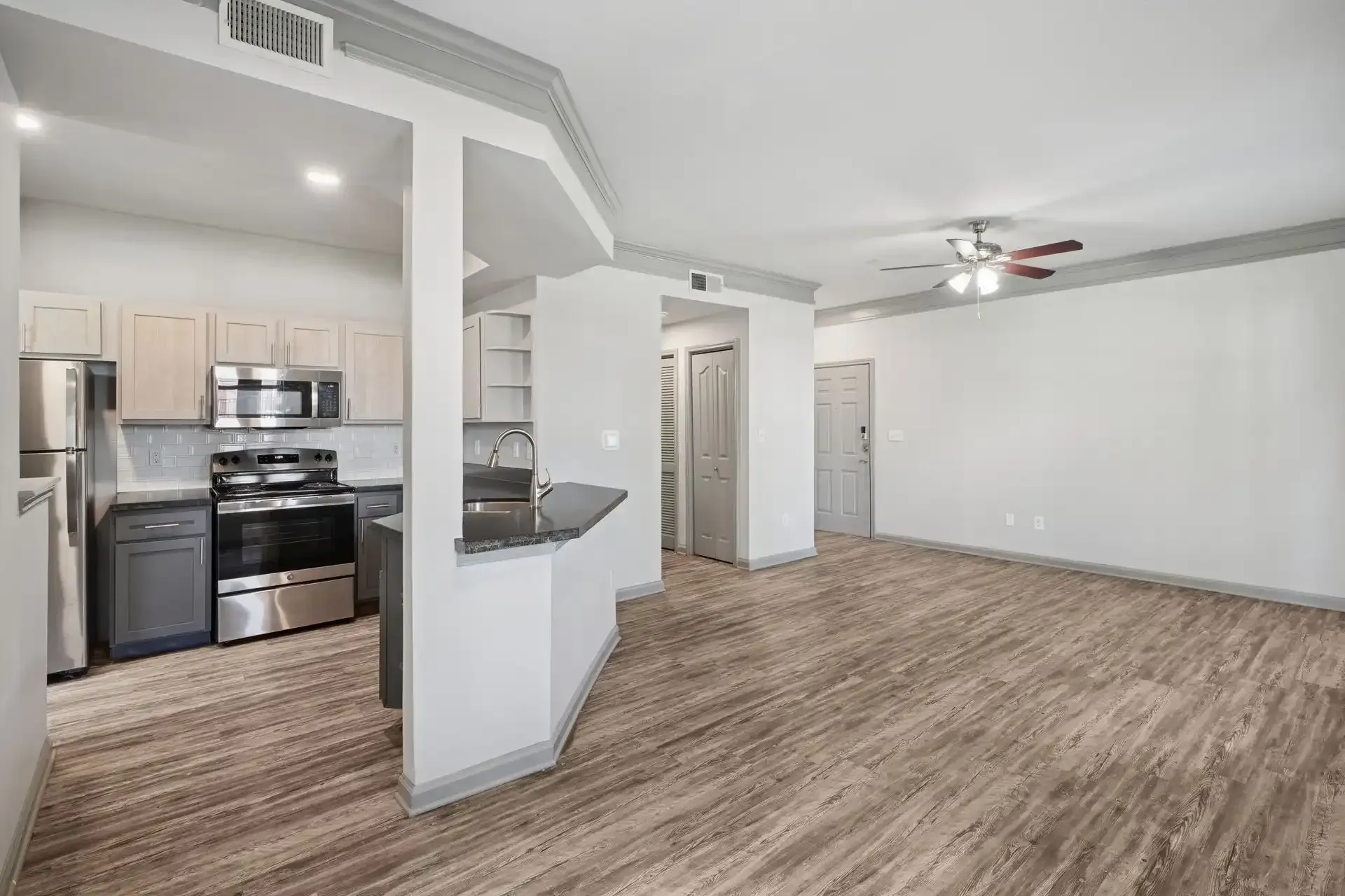 An open-concept kitchen and living area with hardwood floors, stainless steel appliances, and neutral tones.