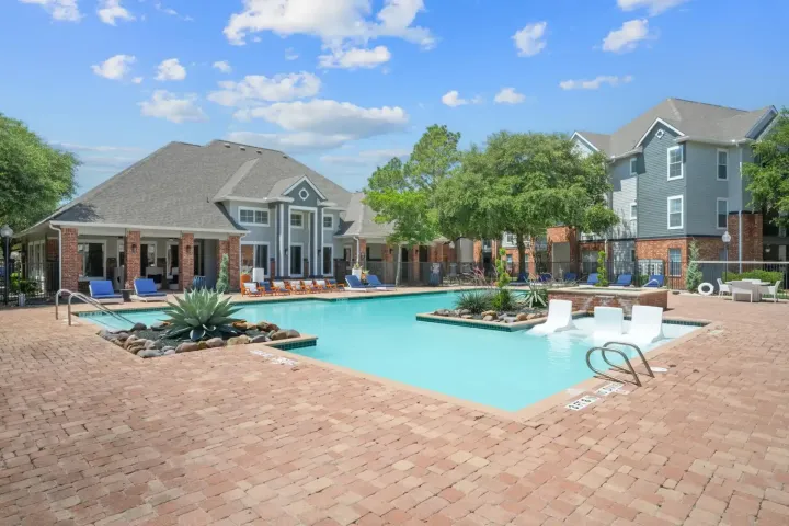 Pool with a brick deck, surrounded by light blue apartment buildings.