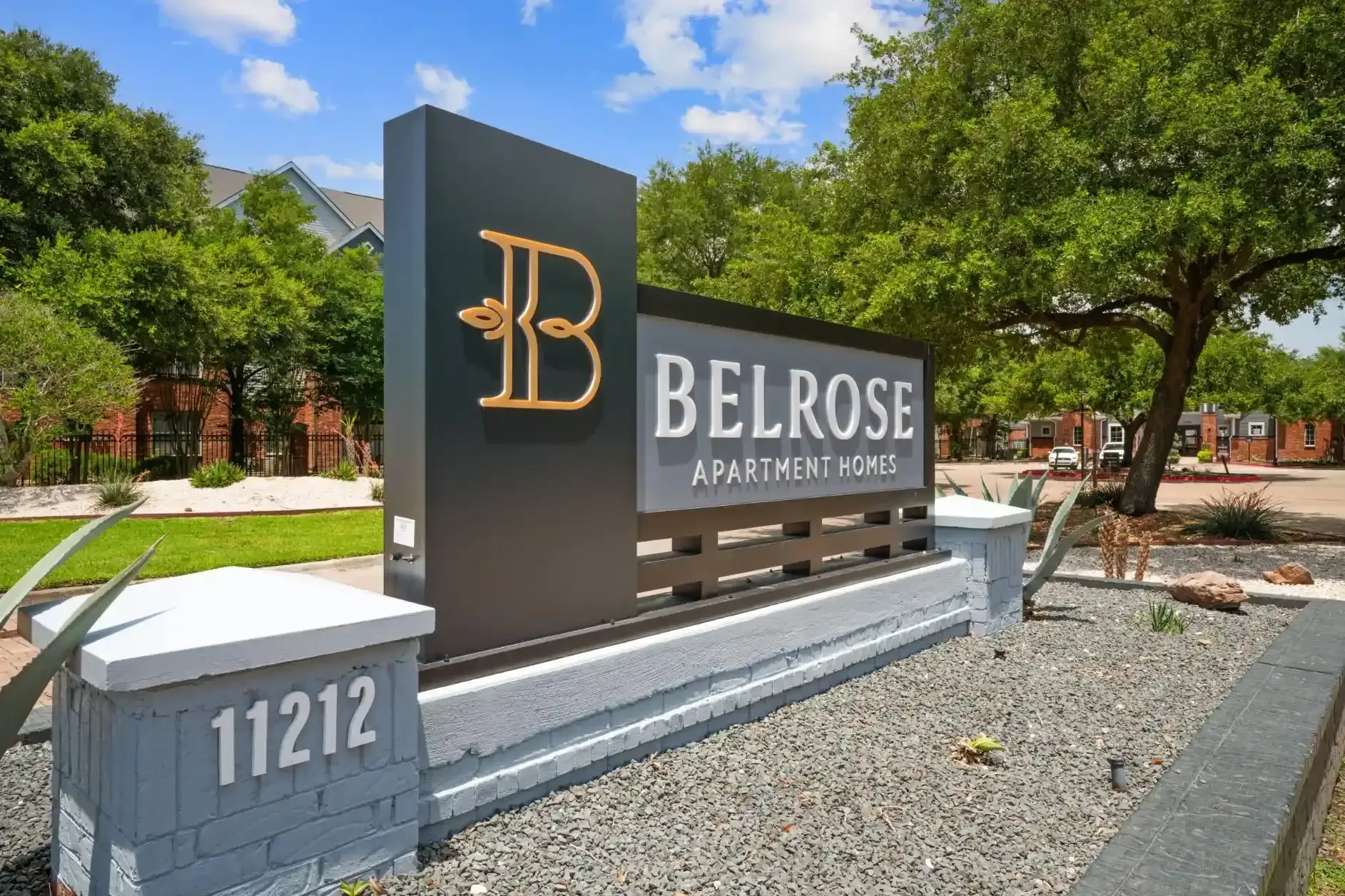 Belrose Apartment Homes sign with address 11212, set in front of a building and trees.