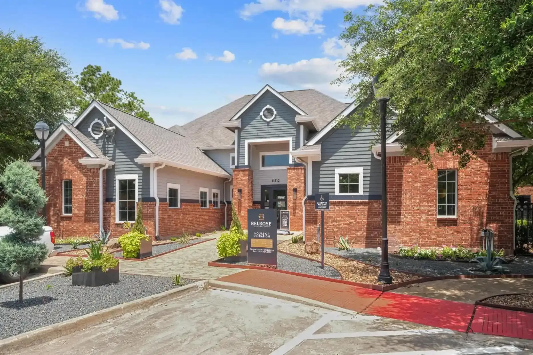 Apartment building with brick facade, blue accents, and landscaping.