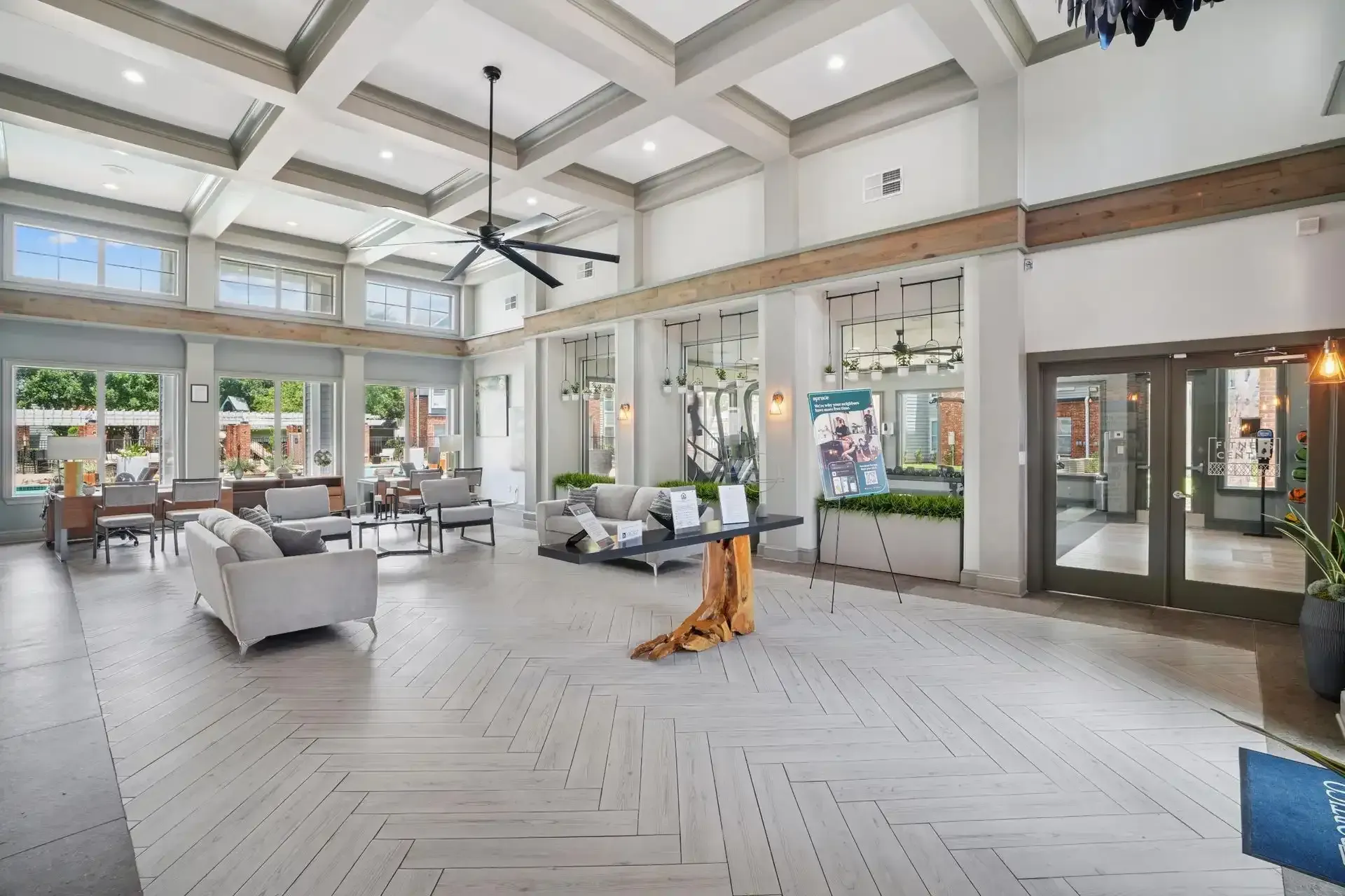 Lobby with couches, tables, and large windows. Neutral color scheme.