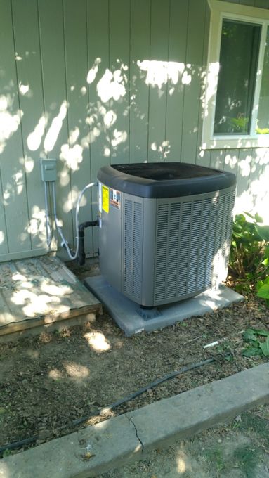 An air conditioner is sitting on the side of a house.