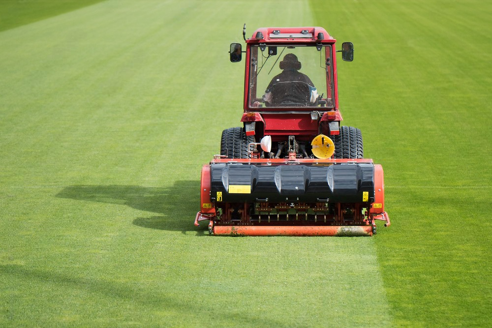 a red tractor is working on a lush green field