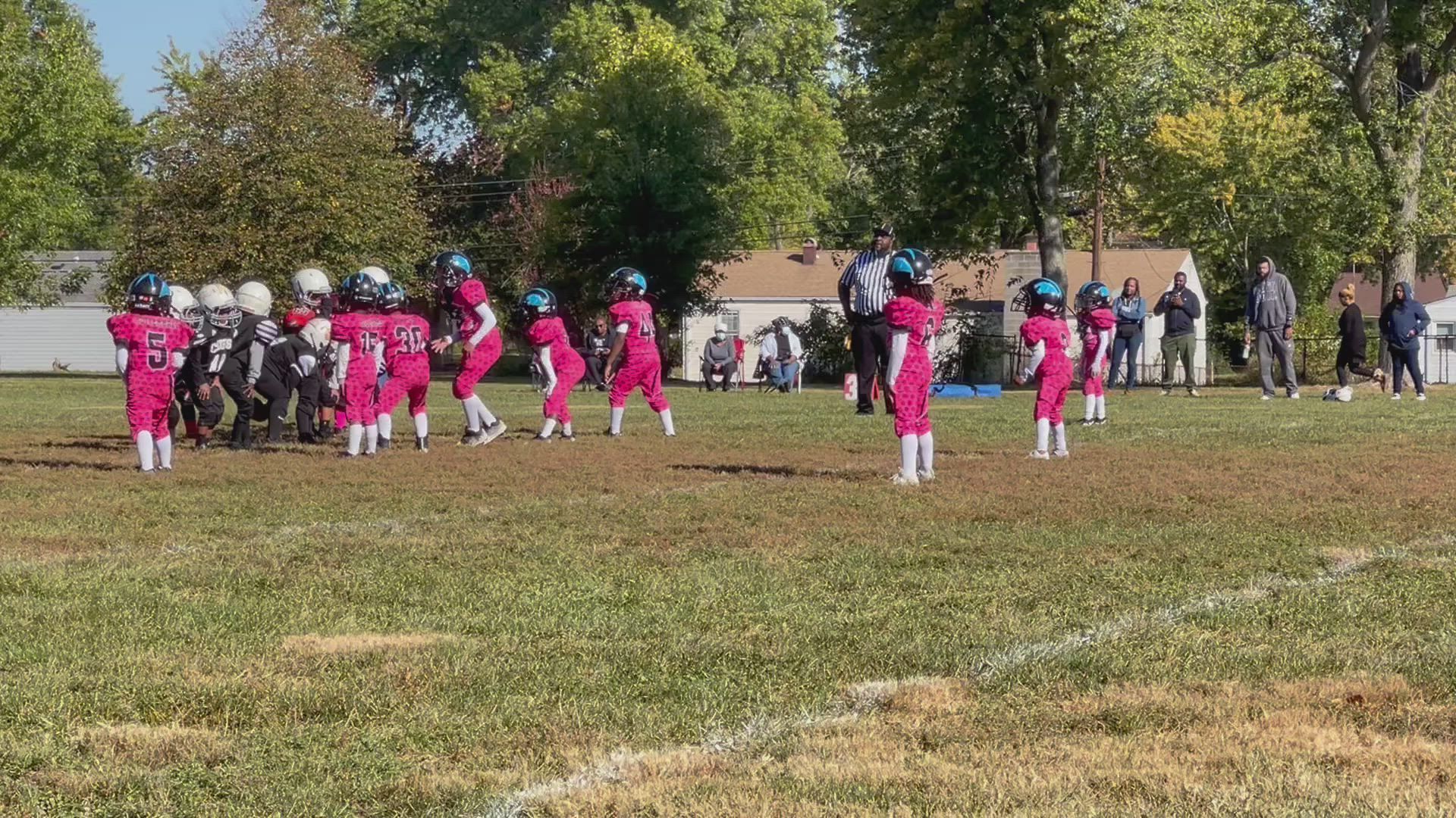 Youth football players in pink uniforms on a field.