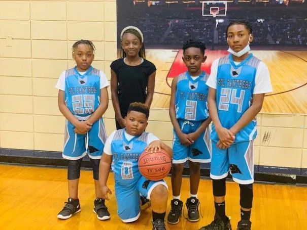 Youth basketball team posing for photo in light blue jerseys.