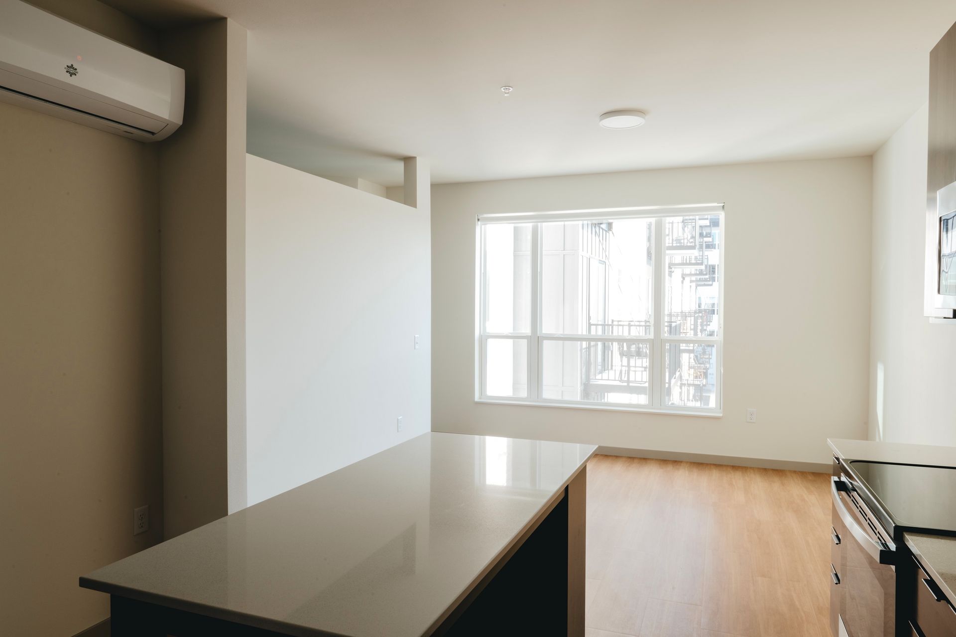 Empty modern kitchen with light wood floors, a window, and a countertop at Revelry in Madison WI.