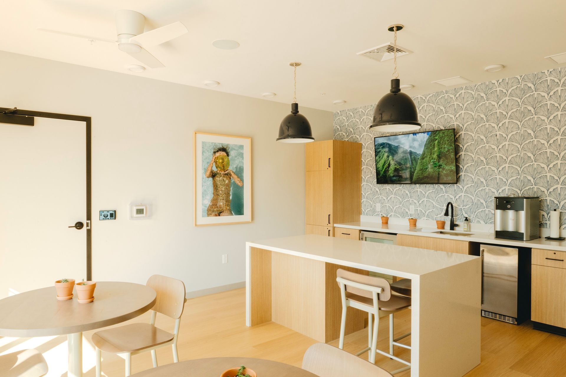 Modern office kitchen with island, light wood cabinets, and seating areas at Revelry in Madison WI.