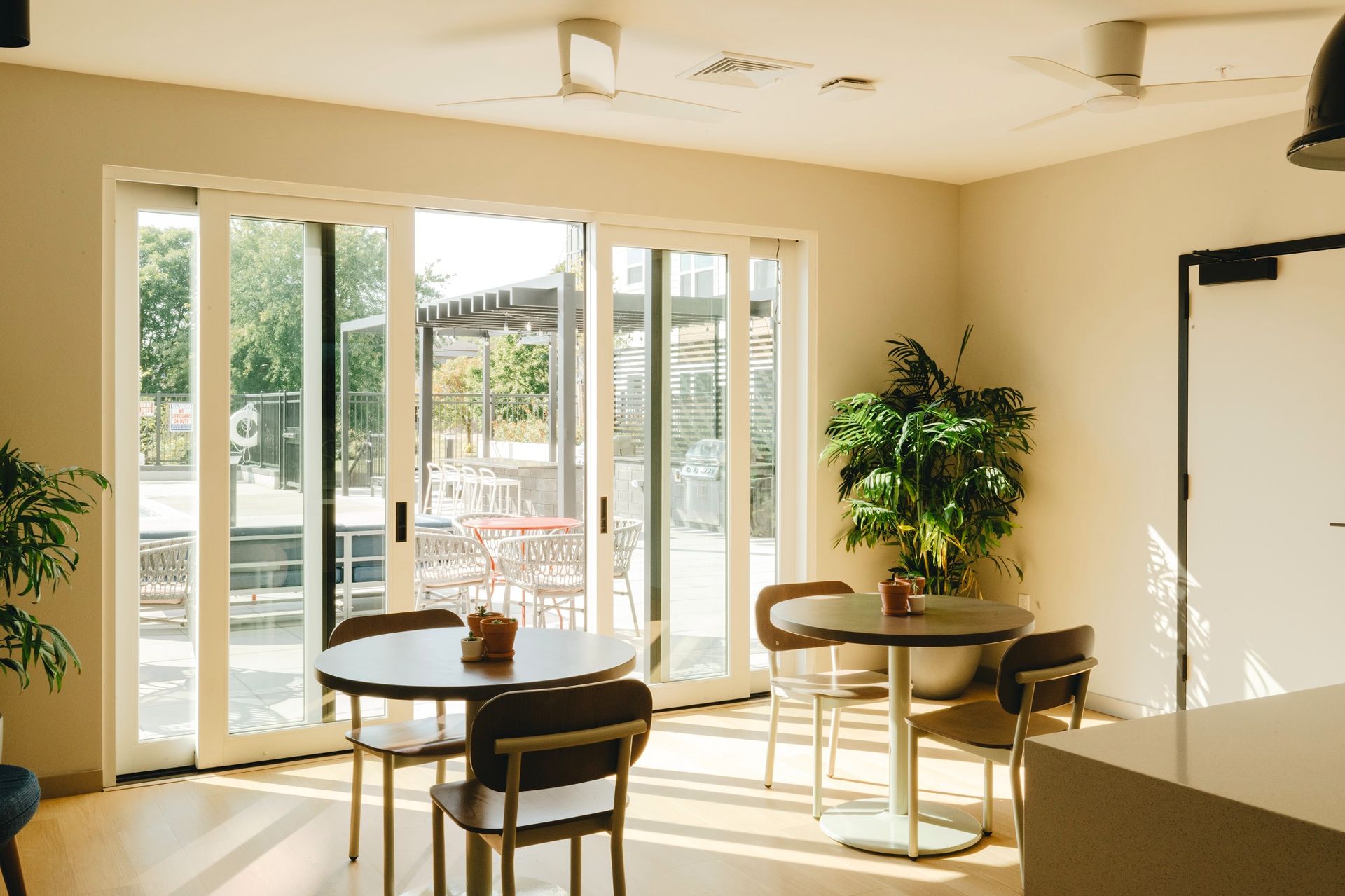 Interior of a cafe with round tables, chairs, large sliding glass doors leading to an outdoor patio at Revelry in Madison WI.