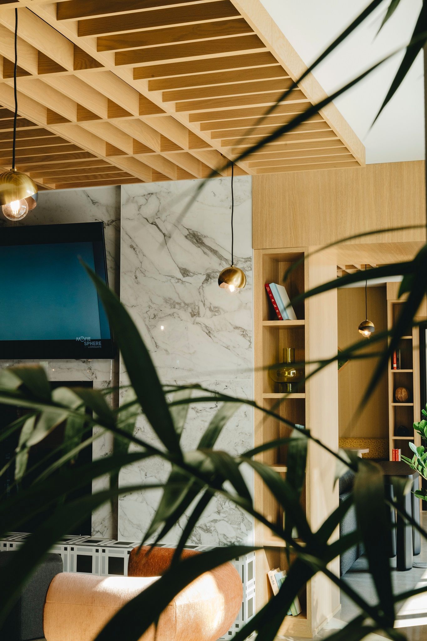 Interior with marble wall, wooden ceiling, built-in shelves, and greenery in the foreground at Revelry in Madison WI.