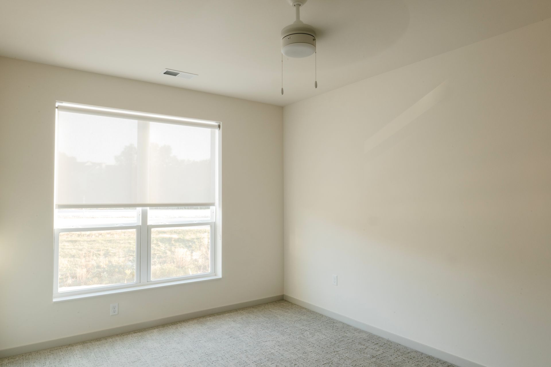 Empty room with window, blinds, ceiling fan, and carpeted floor at Revelry in Madison WI.