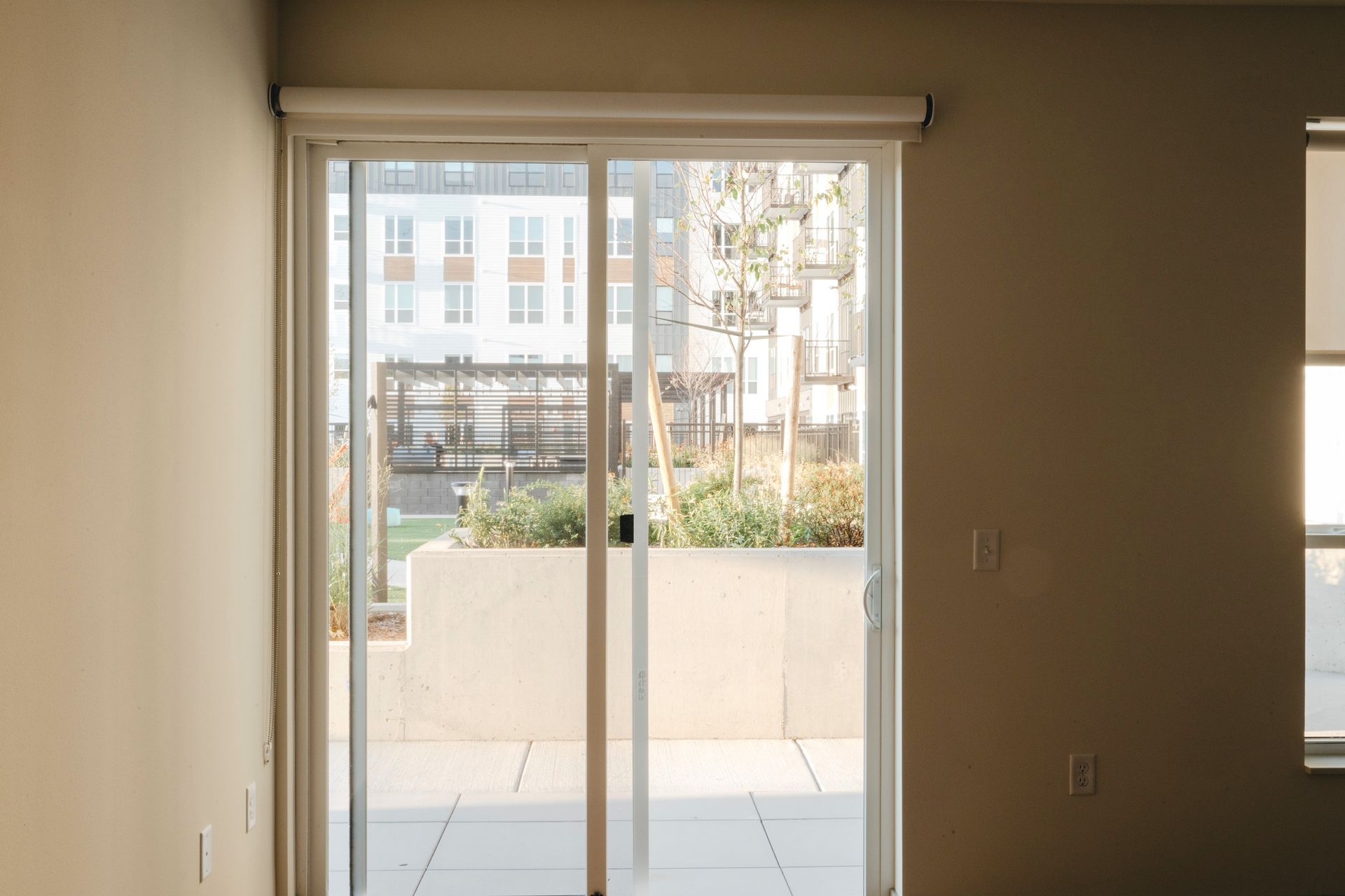 Sliding glass door leads to outdoor patio with plants and buildings visible through the glass at Revelry in Madison WI.