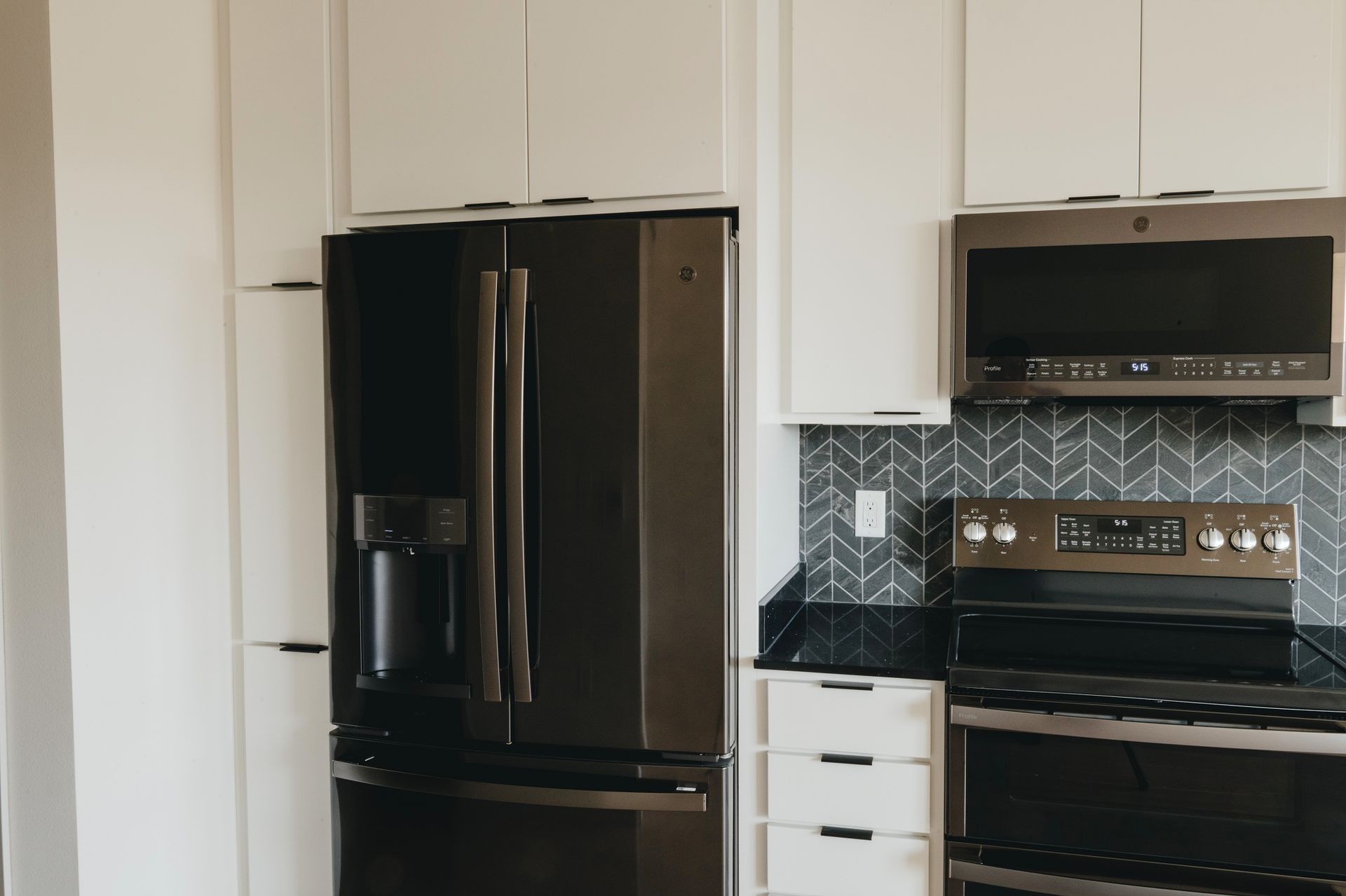 Modern kitchen with white cabinets, dark appliances, and patterned backsplash at Revelry in Madison WI.