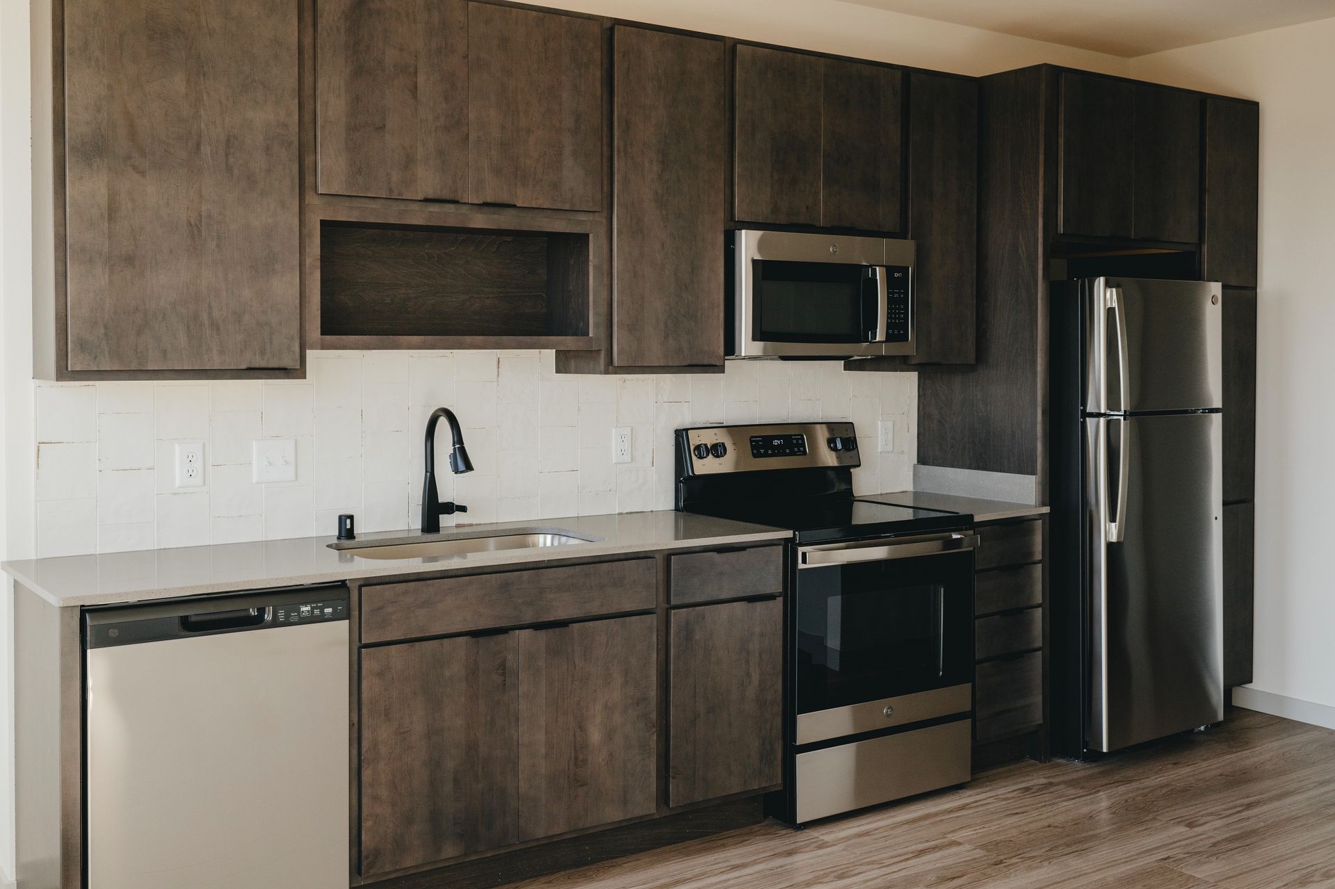 Modern kitchen with gray cabinets, stainless steel appliances, and white backsplash at Revelry in Madison WI.